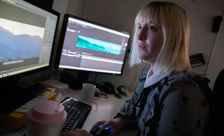 Person arbetar med en panoramabild på två skärmar