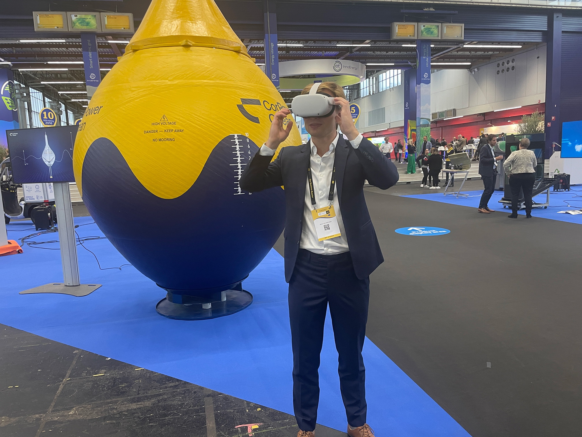 Person provar VR-glasögon framför CorPower Oceans vågkraftsboj i en mässhall